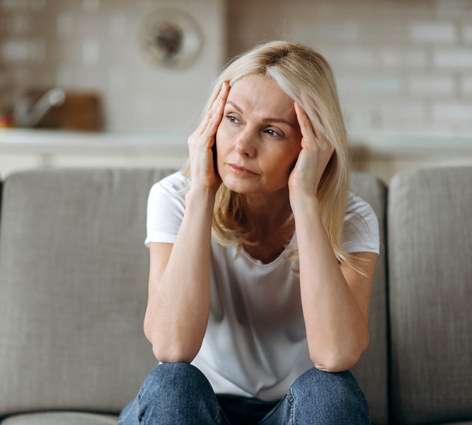 Ältere Frau hält nachdenklich die Hände an den Kopf.