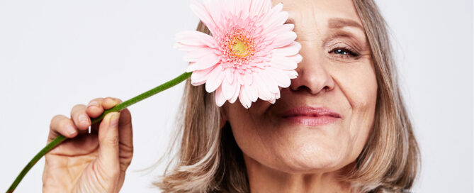 Blog - ältere Frau hält sich Blume vors Gesicht