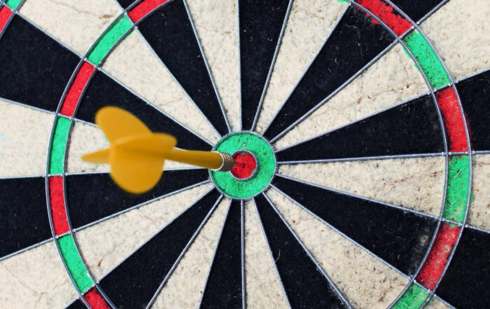 Blog | Perfektionismus | Wachsen im Wechsel Martina Pietsch, Ausschnitt einer Dartscheibe, gelber Pfeil steckt genau in der Mitte