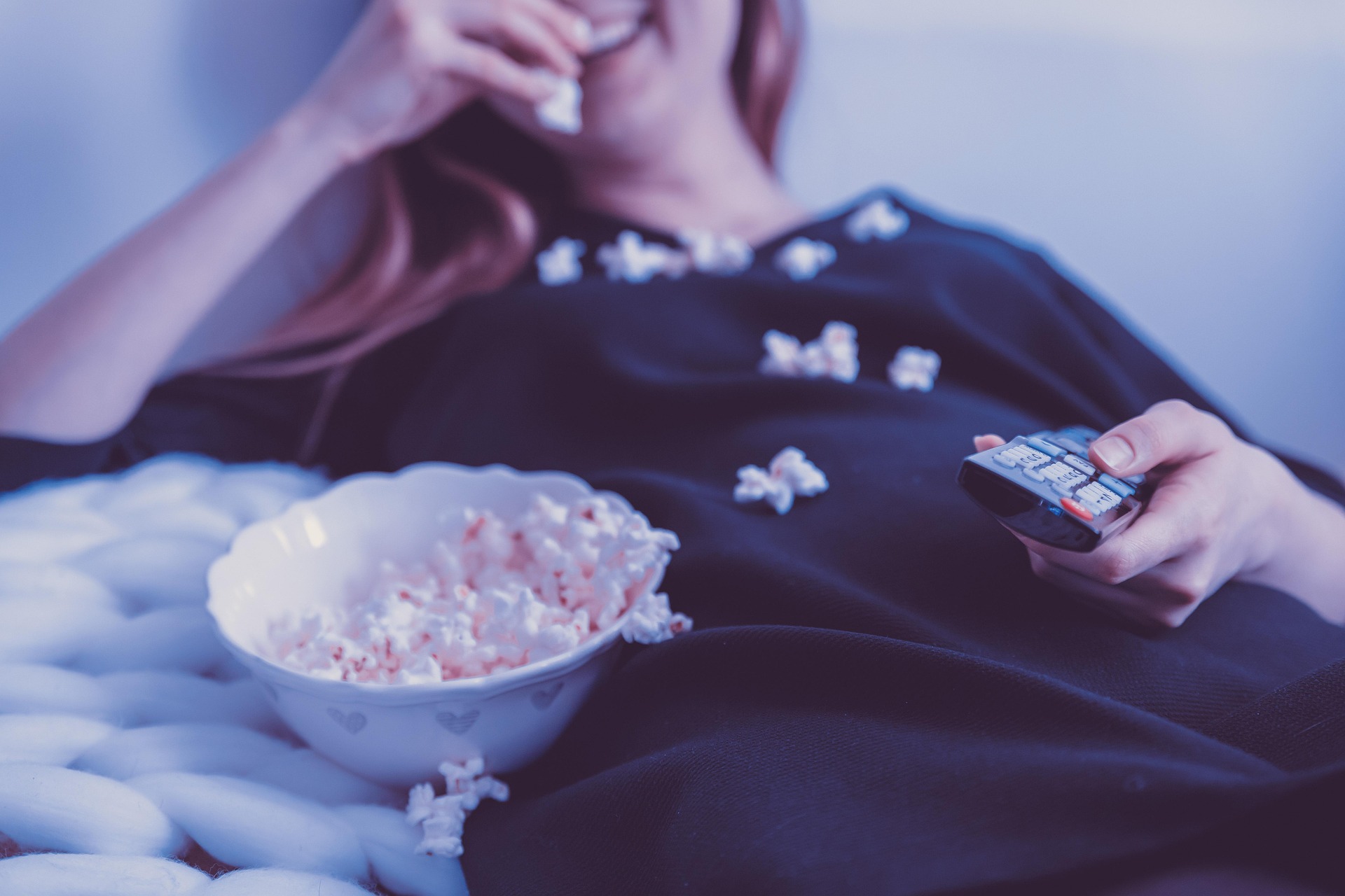 Blog | Priorisieren | Wachsen im Wechsel Martina Pietsch, Frau liegt auf Sofa, Fernbedienung in der Hand, isst Popcorn